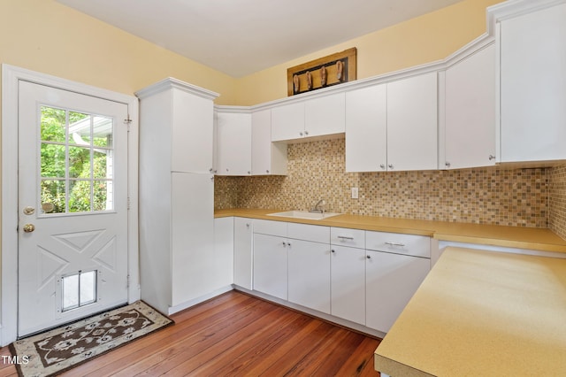 kitchen featuring a sink, light wood finished floors, light countertops, white cabinetry, and backsplash