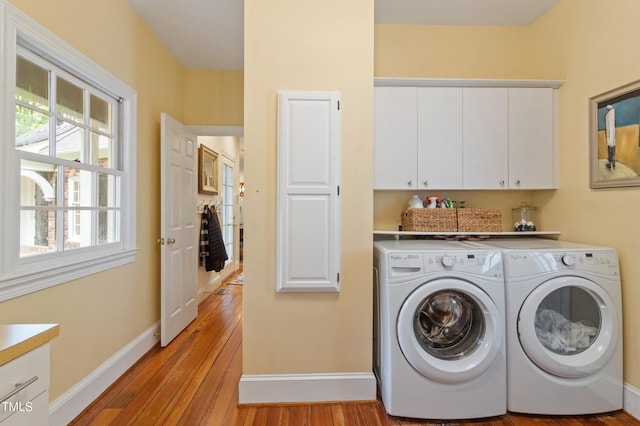 washroom with cabinet space, washing machine and clothes dryer, light wood-style flooring, and baseboards