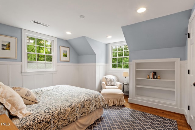 bedroom featuring wood finished floors, a wainscoted wall, and vaulted ceiling