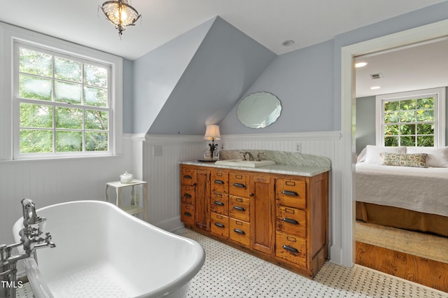 ensuite bathroom featuring a wainscoted wall, a soaking tub, vanity, and tile patterned floors