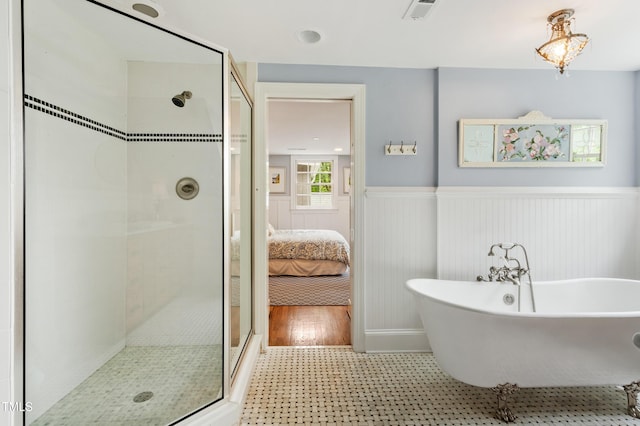 ensuite bathroom with wainscoting, a shower stall, and a freestanding bath