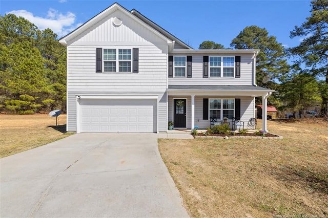traditional-style home with a porch, driveway, a garage, and a front lawn