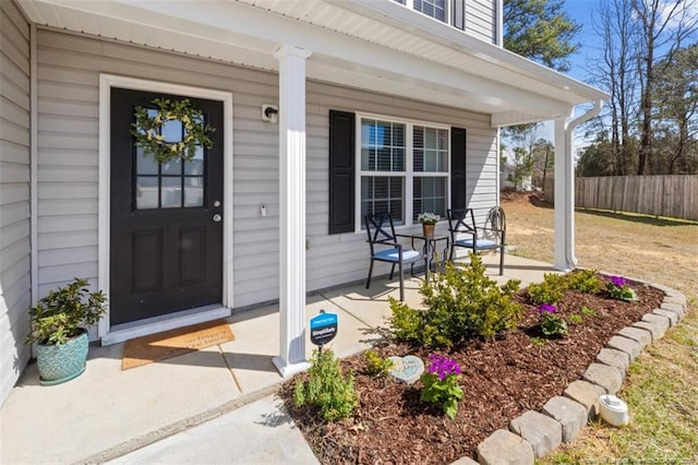 entrance to property featuring fence and covered porch