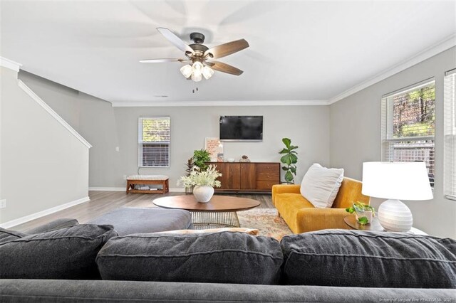 living area featuring ornamental molding, ceiling fan, wood finished floors, and baseboards