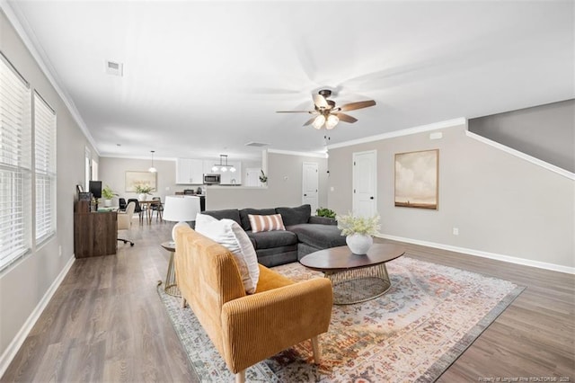 living area featuring visible vents, light wood-type flooring, baseboards, and ceiling fan