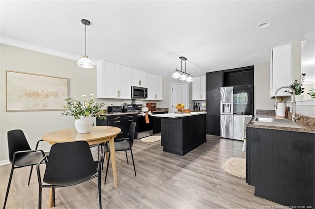 kitchen featuring dark cabinets, light wood-style flooring, a kitchen island, appliances with stainless steel finishes, and a sink