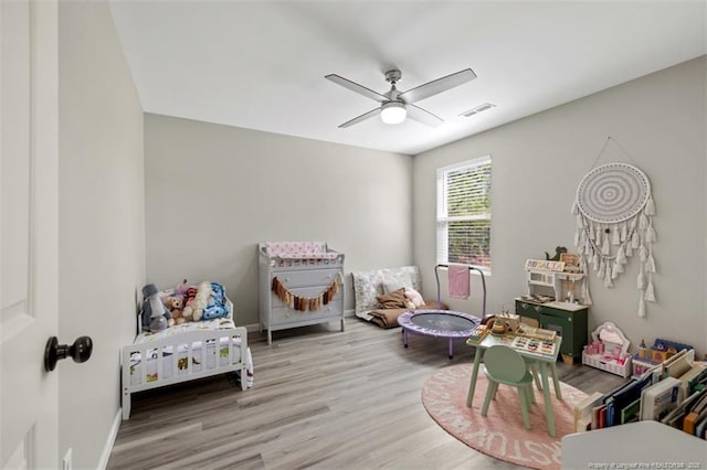 bedroom featuring wood finished floors, baseboards, a ceiling fan, and visible vents