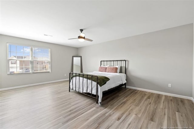 bedroom featuring visible vents, baseboards, a ceiling fan, and light wood-style floors