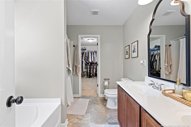 bathroom featuring toilet, double vanity, a sink, and visible vents