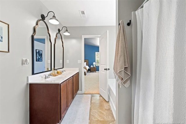full bath with a sink, visible vents, double vanity, and connected bathroom