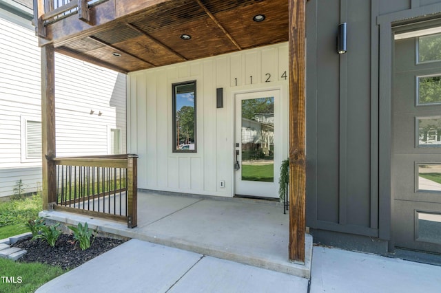 entrance to property with board and batten siding and a patio area