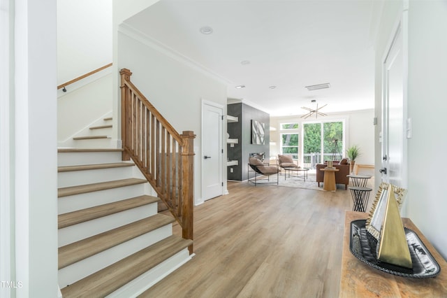 staircase with crown molding and wood finished floors