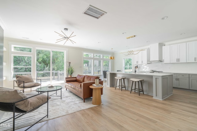 living room with ornamental molding, light wood-style flooring, a chandelier, and recessed lighting