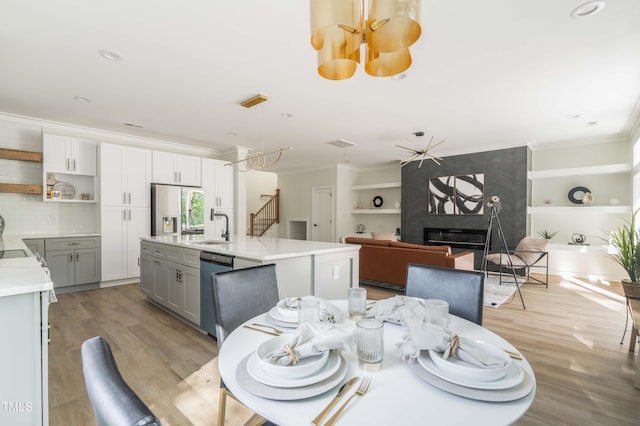 dining space with crown molding, light wood-type flooring, a premium fireplace, built in features, and recessed lighting