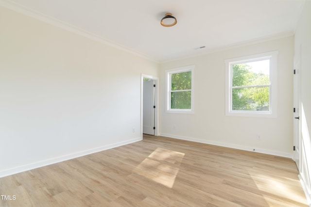 empty room featuring ornamental molding, light wood finished floors, and baseboards