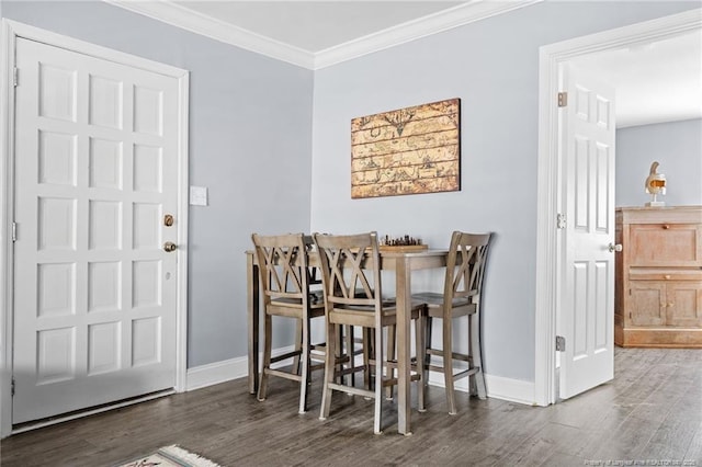 dining space with baseboards, wood finished floors, and ornamental molding