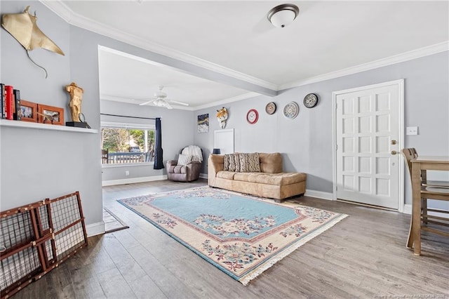 living area featuring crown molding, wood finished floors, and baseboards