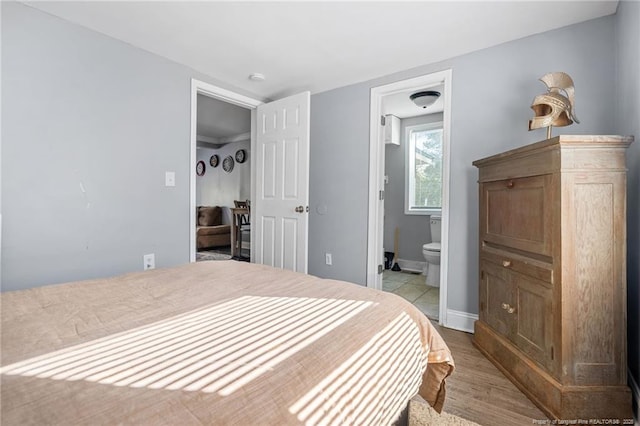 bedroom with connected bathroom and light wood-style flooring