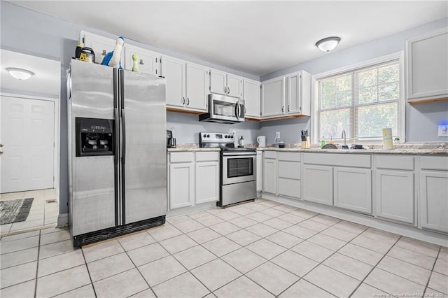 kitchen featuring a sink, light stone countertops, white cabinetry, and stainless steel appliances