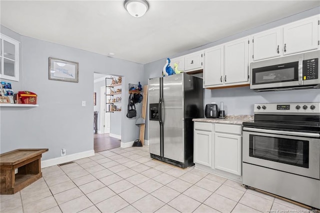 kitchen featuring light tile patterned floors, baseboards, light countertops, appliances with stainless steel finishes, and white cabinetry