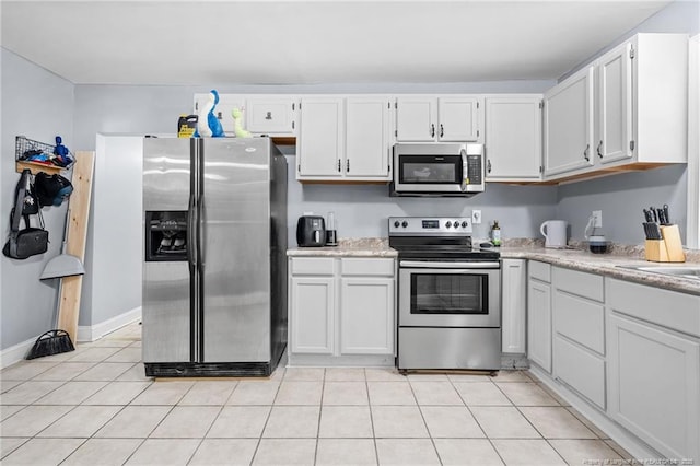 kitchen featuring light tile patterned floors, white cabinets, stainless steel appliances, and light countertops