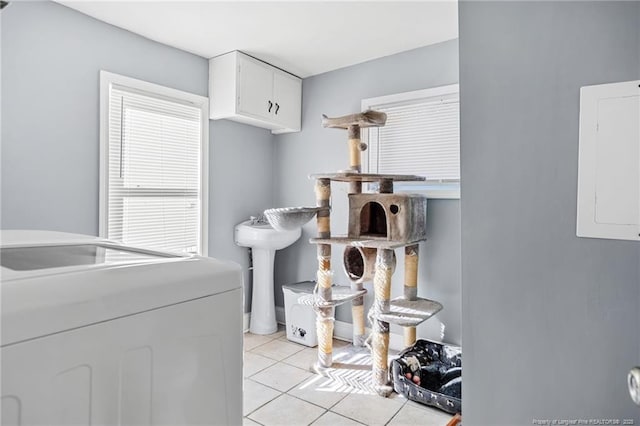 washroom with electric panel, washer / clothes dryer, cabinet space, light tile patterned floors, and baseboards