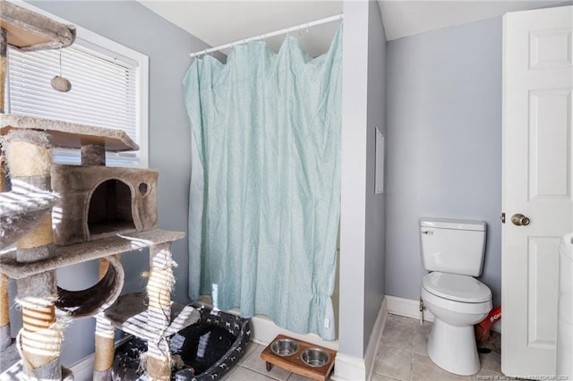 bathroom featuring tile patterned flooring, curtained shower, toilet, and baseboards