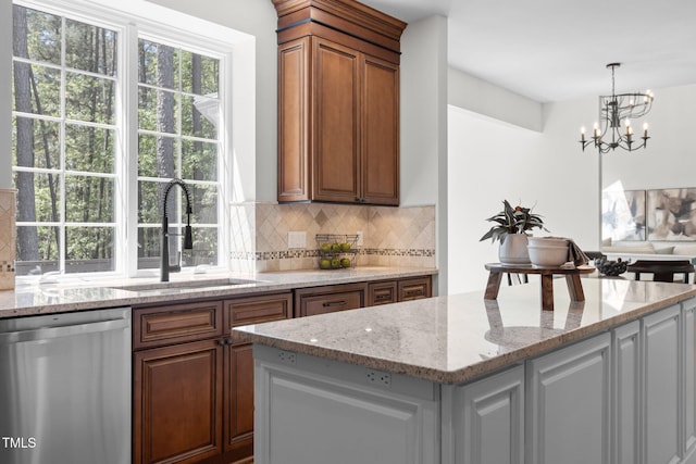 kitchen featuring tasteful backsplash, light stone countertops, stainless steel dishwasher, and a sink