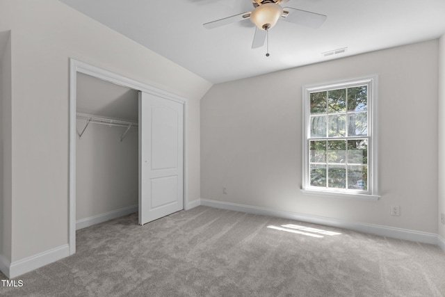 unfurnished bedroom with carpet flooring, vaulted ceiling, baseboards, visible vents, and a closet