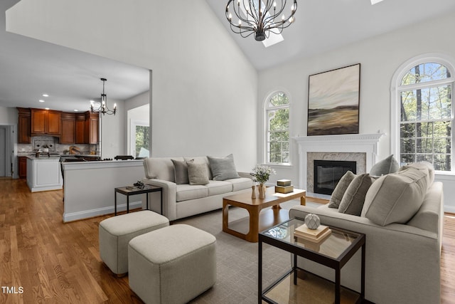 living room with recessed lighting, an inviting chandelier, wood finished floors, a premium fireplace, and high vaulted ceiling