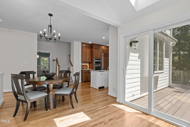 dining space with baseboards, recessed lighting, a notable chandelier, light wood-style floors, and a skylight