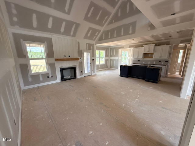 living room with a fireplace, baseboards, and high vaulted ceiling