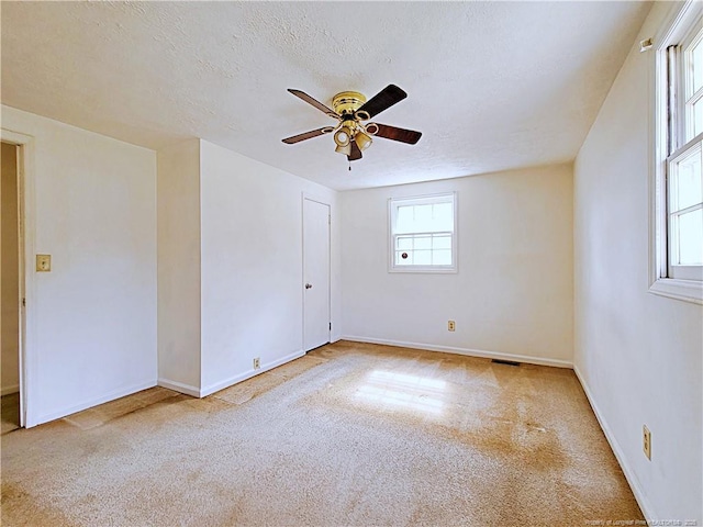 carpeted spare room featuring visible vents, baseboards, a textured ceiling, and ceiling fan