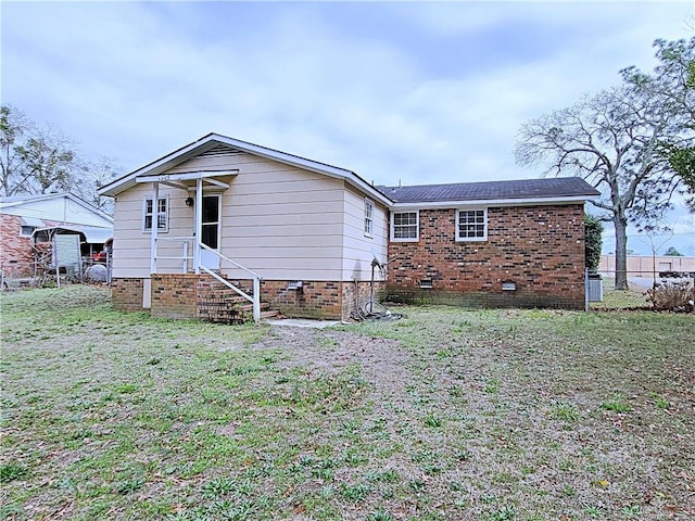 rear view of property featuring a lawn and fence