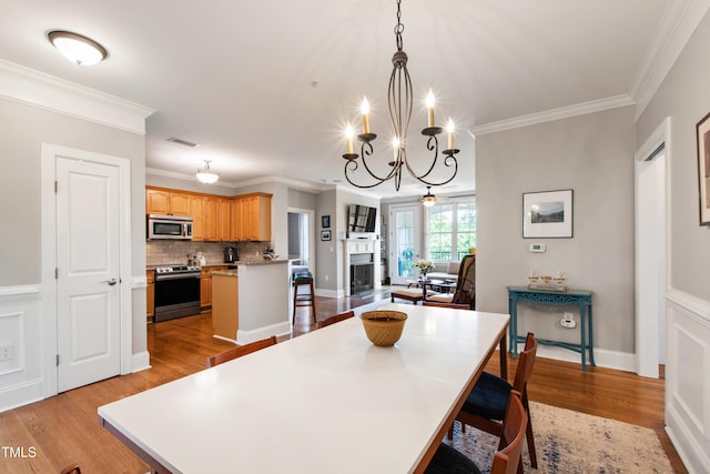 340 Allister Dr Unit 201, Raleigh, NC 27609 - dining space with crown molding, a fireplace, ceiling fan with notable chandelier, light wood-type flooring, and visible vents
