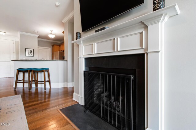 340 Allister Dr Unit 201, Raleigh, NC 27609 - room details with crown molding, a tiled fireplace, wood finished floors, baseboards, and freestanding refrigerator