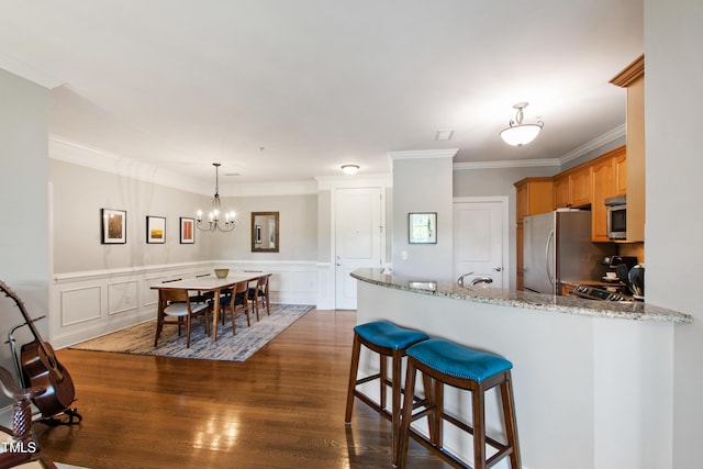 340 Allister Dr Unit 201, Raleigh, NC 27609 - kitchen with crown molding, a peninsula, dark wood-style floors, appliances with stainless steel finishes, and a notable chandelier