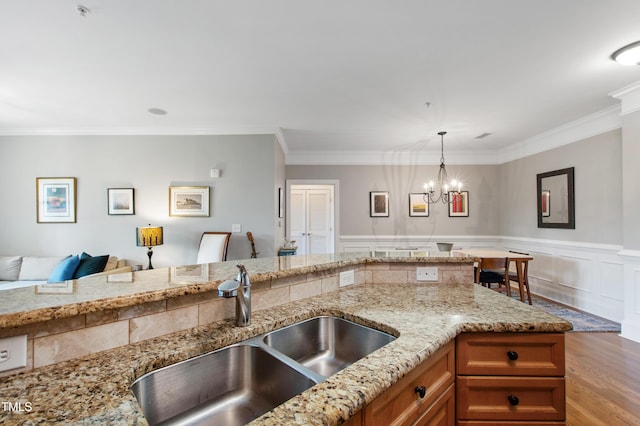 340 Allister Dr Unit 201, Raleigh, NC 27609 - kitchen with brown cabinets, a sink, light stone counters, an inviting chandelier, and light wood-style flooring