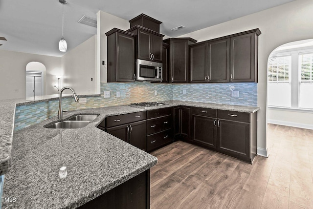 kitchen with light stone countertops, arched walkways, a sink, and appliances with stainless steel finishes