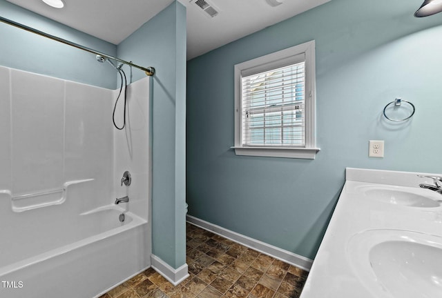 full bath with baseboards, stone finish floor, a sink, and visible vents