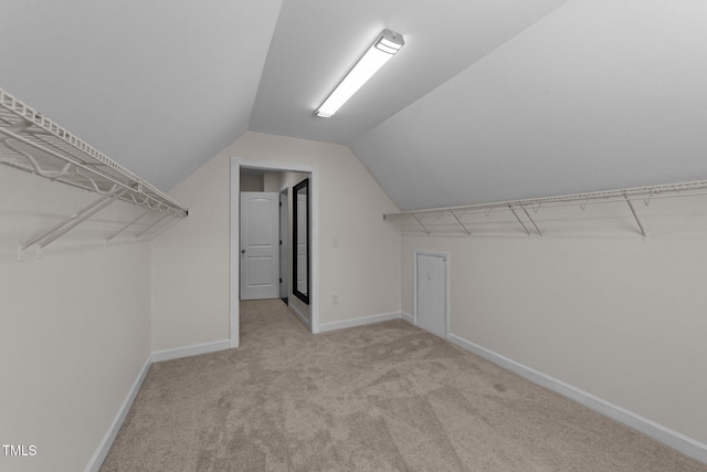 walk in closet with vaulted ceiling and carpet
