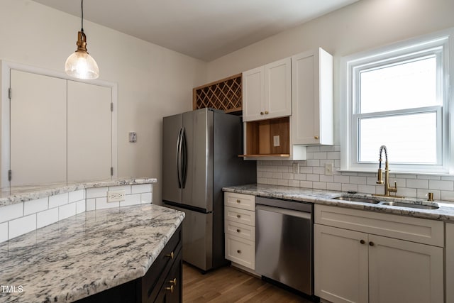 118 Riverwood Dr, Fuquay Varina, NC 27526 - kitchen with light stone counters, a sink, appliances with stainless steel finishes, pendant lighting, and backsplash