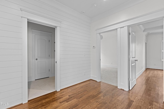 unfurnished bedroom with wood finished floors, wood walls, and ornamental molding