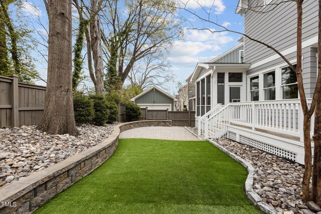 view of yard featuring a patio, a fenced backyard, and a sunroom