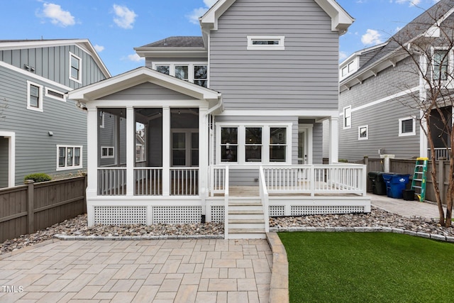 back of property with fence, a yard, and a sunroom