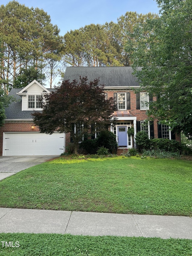 view of front of property featuring brick siding, a front lawn, an attached garage, roof with shingles, and driveway