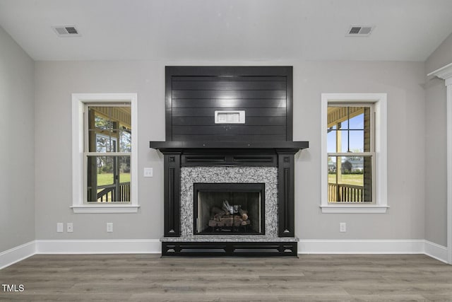 unfurnished living room with wood finished floors, baseboards, and visible vents