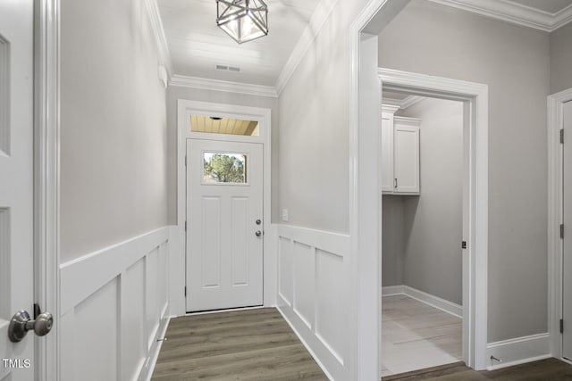 entryway with a decorative wall, visible vents, ornamental molding, dark wood-style floors, and wainscoting