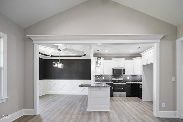 kitchen with white cabinetry, lofted ceiling, a sink, light stone counters, and appliances with stainless steel finishes