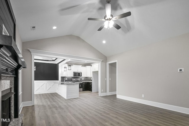 unfurnished living room featuring a fireplace, wood finished floors, lofted ceiling, visible vents, and ceiling fan
